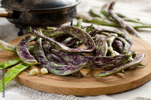 Purple speckled kidney beans with pods on wooden round Board photo