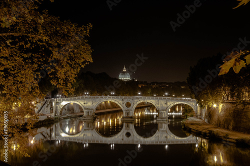 Puente sobre el río Tiber en Roma. Cúpula de San Pedro de fondo photo