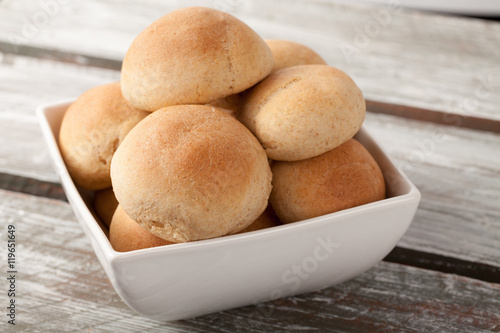 Fresh homemade whole wheat dinner rolls in a white square bowl