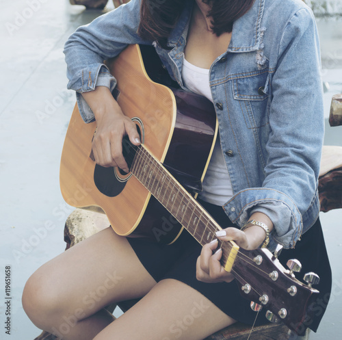 Asian woman playing guitar.