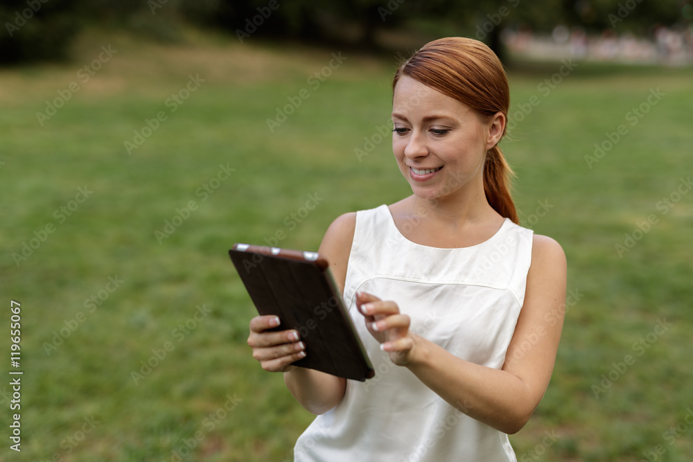 Caucasian woman in city park using tablet computer Caucasian woman in city park using tablet computer