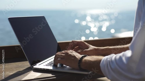 man looking for information in the laptop on the waterfront on sea background