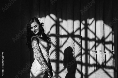 Shadow of beautiful woman lies on the wall while she poses smili