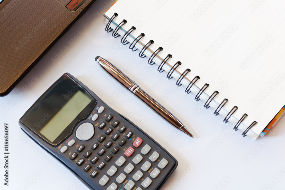 working desk with calculator and laptop, pen, notebook on white working desk with calculator and laptop, pen, notebook on white