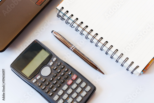 working desk with calculator and laptop, pen, notebook on white