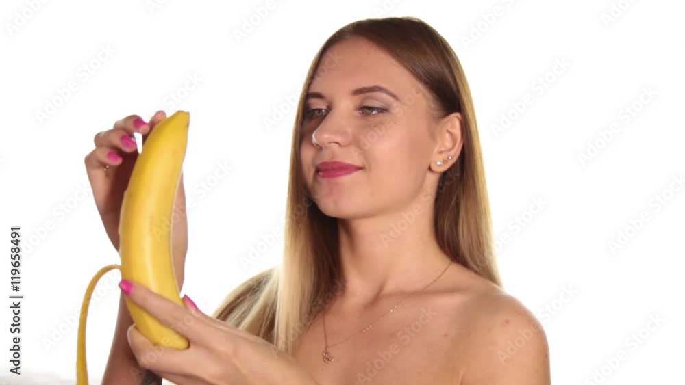 naked young woman wears red lipstick and has her hair down, and brushed, peeling and eating a big banana. healthy food - strong teeth concept. On a white background naked young woman wears red lipstick and has her hair down, and brushed, peeling and eating a big banana. healthy food - strong teeth concept. On a white background