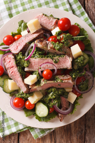 Sliced beef steak with a salad of fresh vegetables close-up. Vertical top view 
