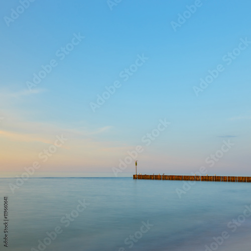 sunset on the beach with a wooden breakwater, long exposure
