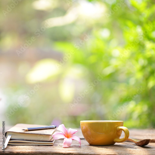 yellow coffee cup and notebooks on wooden table