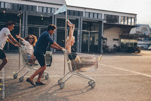 Young friends racing with shopping carts photo