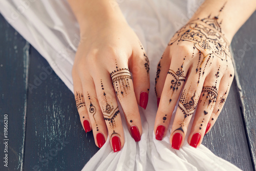 Red manicured hands with Mehndi