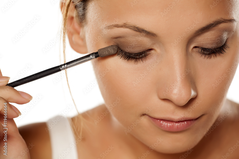 young beautiful woman applied eye shadow with applicator..