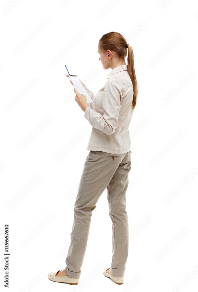 back view of stands woman takes notes in a notebook. Isolated over white background. Skinny girl in white denim suit instructs reading from a notebook. back view of stands woman takes notes in a notebook. Isolated over white background. Skinny girl in white denim suit instructs reading from a notebook.