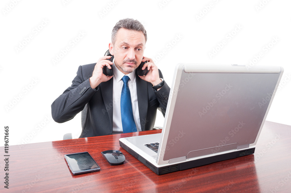 Young manager with headphones reading something on laptop Young manager with headphones reading something on laptop