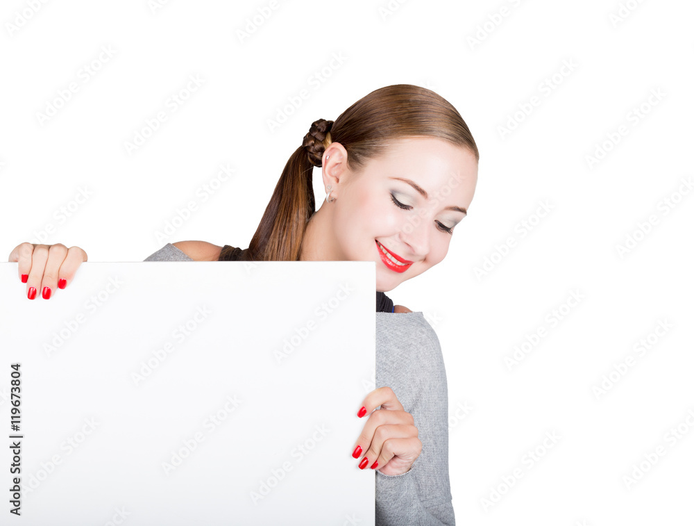 Smiling happy young woman standing behind and leaning on a white blank billboard or placard, expresses different Smiling happy young woman standing behind and leaning on a white blank billboard or placard, expresses different