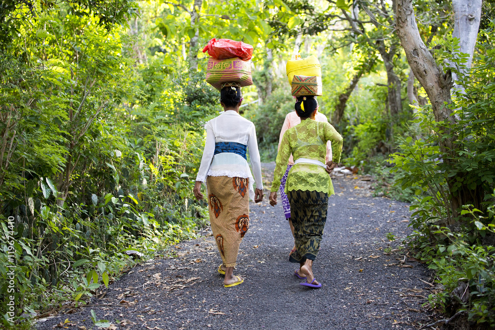 NUSA PENIDA, INDONESIA - AUGUST 13 2016 : Hindu women carry on their heads offerings, August 13. 2016 in - Nusa Penida, Indonesia