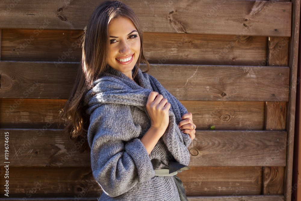 Girl is wearing knitted clothes near wooden wall Girl is wearing knitted clothes near wooden wall