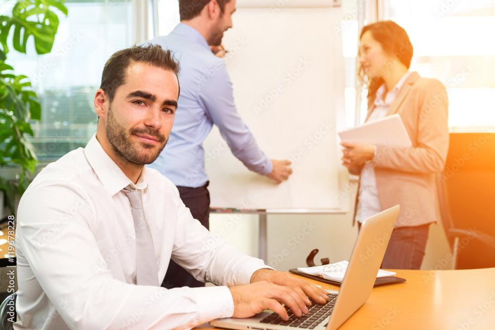 Young attractive businessman working at the office with associat Young attractive businessman working at the office with associat