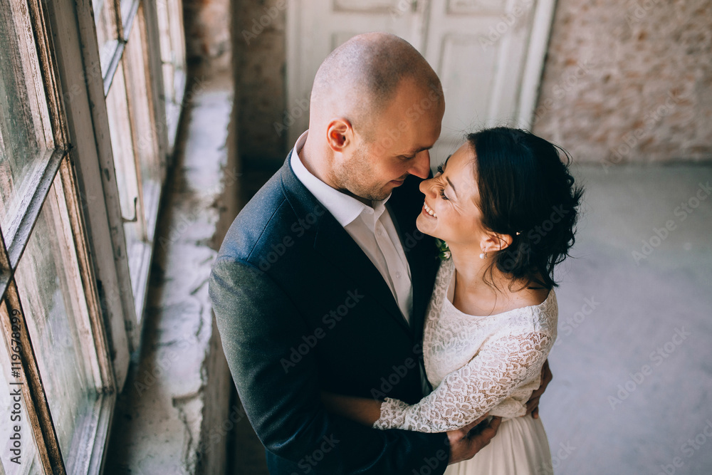 happy newly married couple posing by the window. Loft happy newly married couple posing by the window. Loft