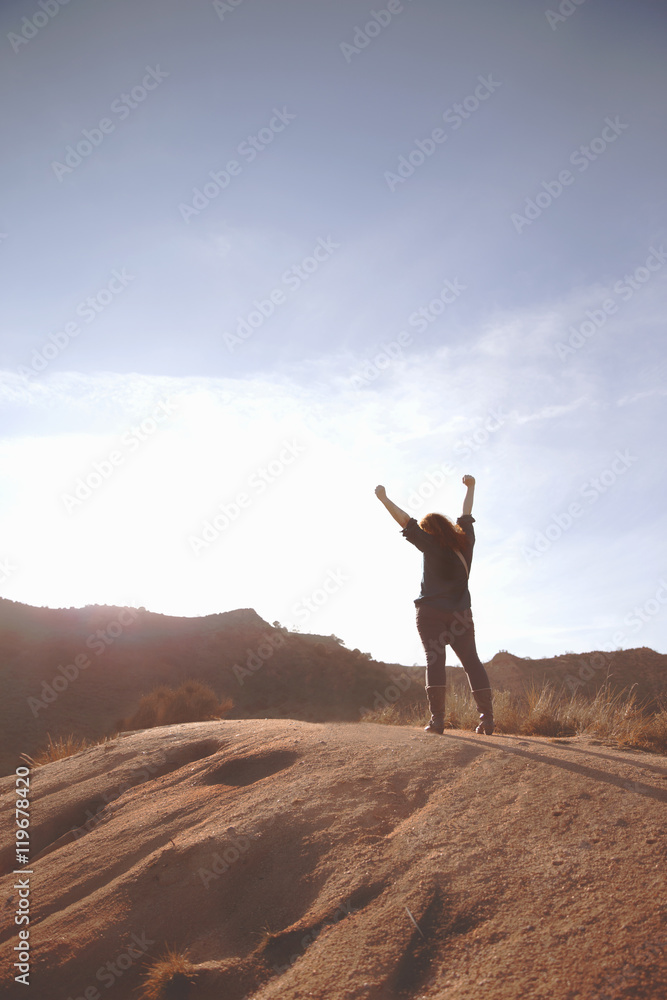 Successful woman with arms raised on sand Successful woman with arms raised on sand