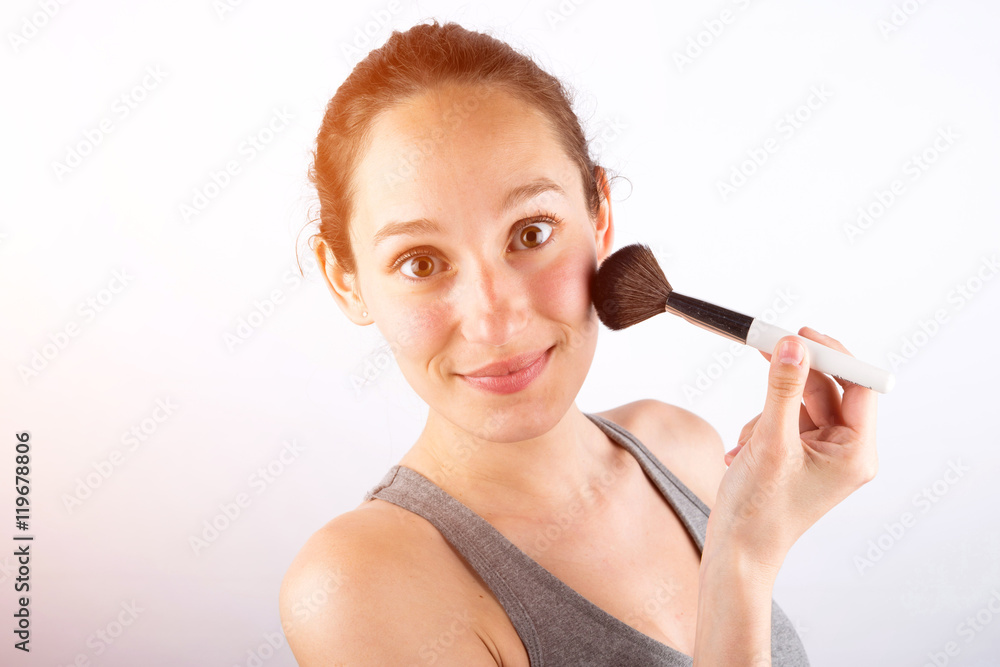 Young attractive woman applying powder wiith brush on her face Young attractive woman applying powder wiith brush on her face
