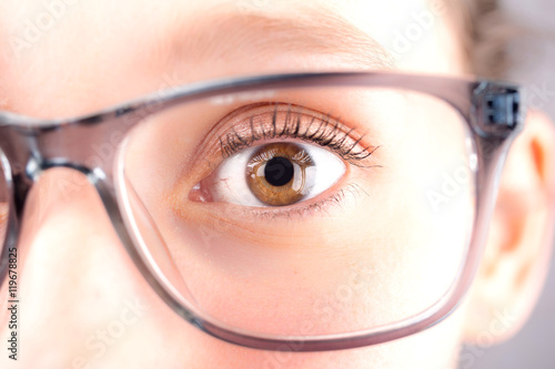 Detailed close up of an brown eye behind glasses in high definit photo