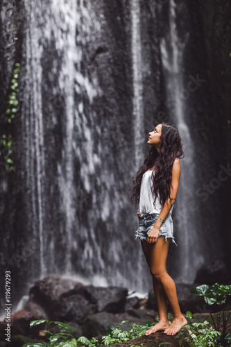 Beautiful brunette woman enjoying near waterfall