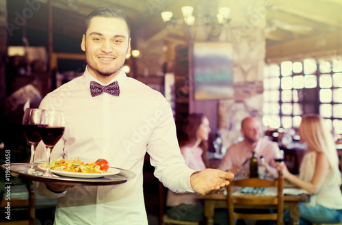 Waiter with restaurant guests at table