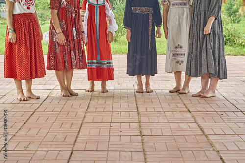 Girls in folk dresses standing barefoot on the concert of folk music outdoors 