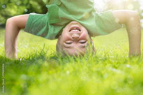 Obraz na plátně Young boy doing a headstand on the grass