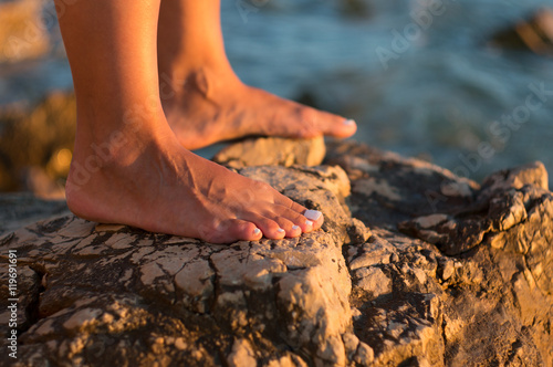 Εκτύπωση καμβά bare woman's feet on rocky beach