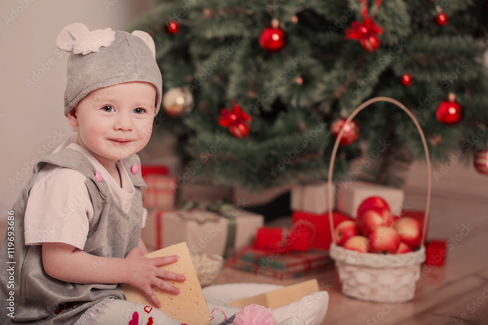 Little child in festive suit of mouse sits in sledges near the Little child in festive suit of mouse sits in sledges near the