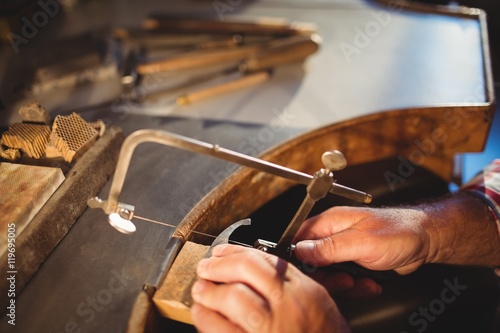 Goldsmith shaping metal with coping saw