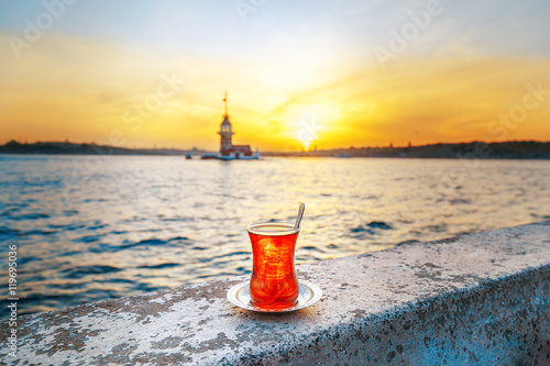 Istanbul welcome concept. Glass of tea on parapet at Maiden tower background. Sunset time scene.