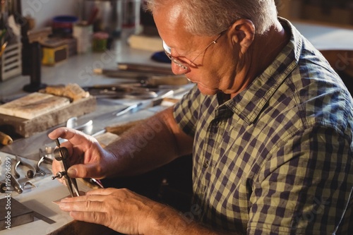 Goldsmith working with divider compass