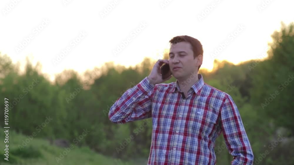 At sunset, a young man talking on the phone At sunset, a young man talking on the phone