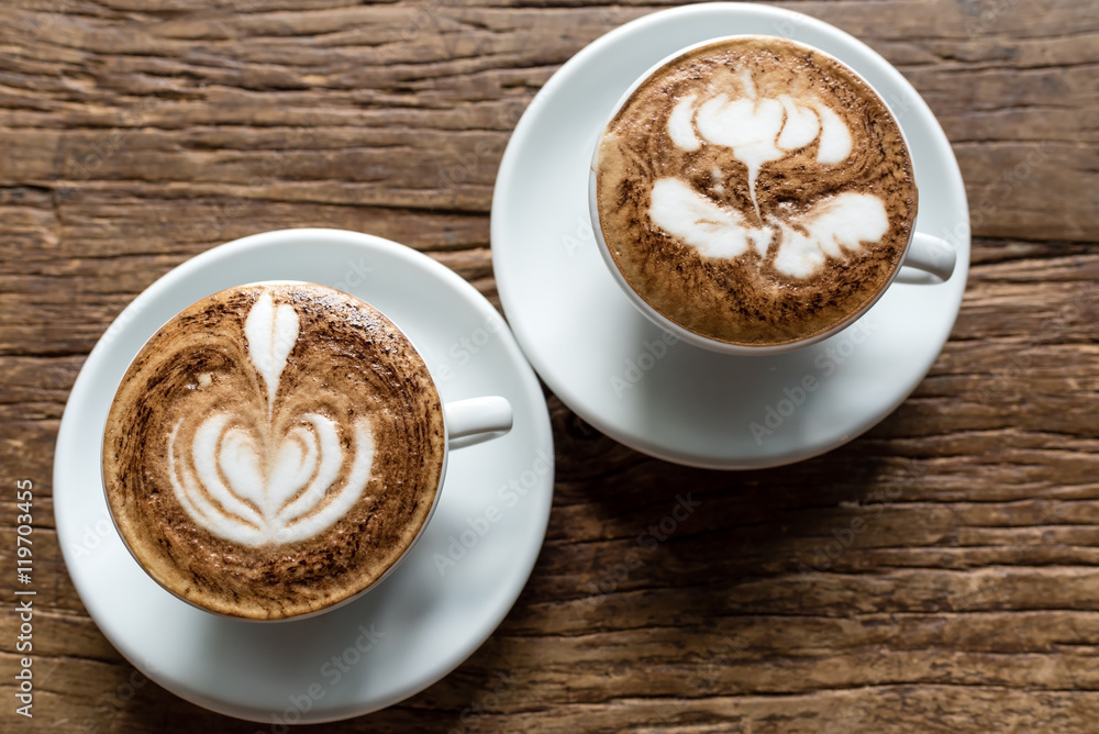 Two Hot cappuccino in white cup and plate on Wooden Background table Two Hot cappuccino in white cup and plate on Wooden Background table