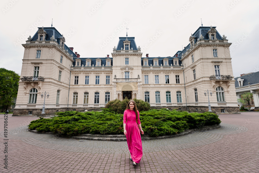 young girl in pink dress near monumental castle