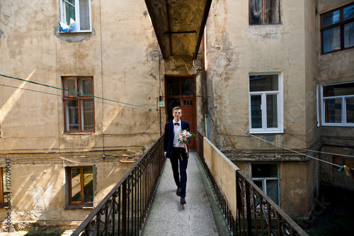 Handsome groom goes .through old balcony © IVASHstudio