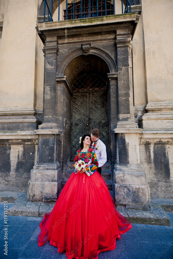 Sweet wedding couple near old church's entrance