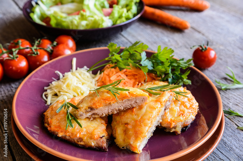 Baked pork cutlets coated in cheese and carrot with salad