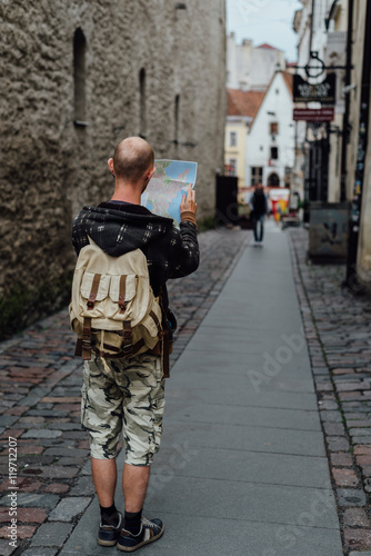 Young man traveler looking city map in old town