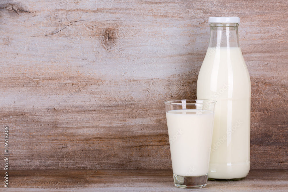 Milch im Glas und in der Flasche auf Holz Stein Hintergrund. Milch im Glas und in der Flasche auf Holz Stein Hintergrund.