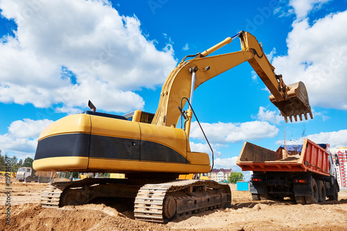 Loader excavator moving earth into dumper truck photo