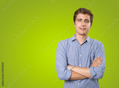 Satisfied young man with arms crossed on green background © agongallud