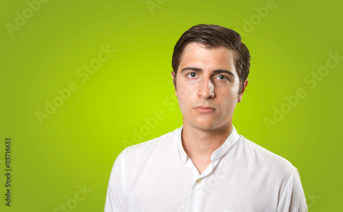 Close up of a serious young man on green background © agongallud
