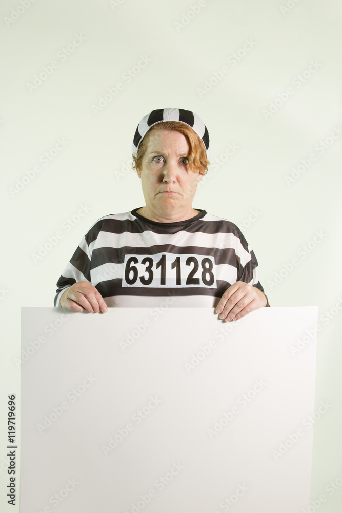 Sad woman in prison uniform with white sign Sad woman in prison uniform with white sign
