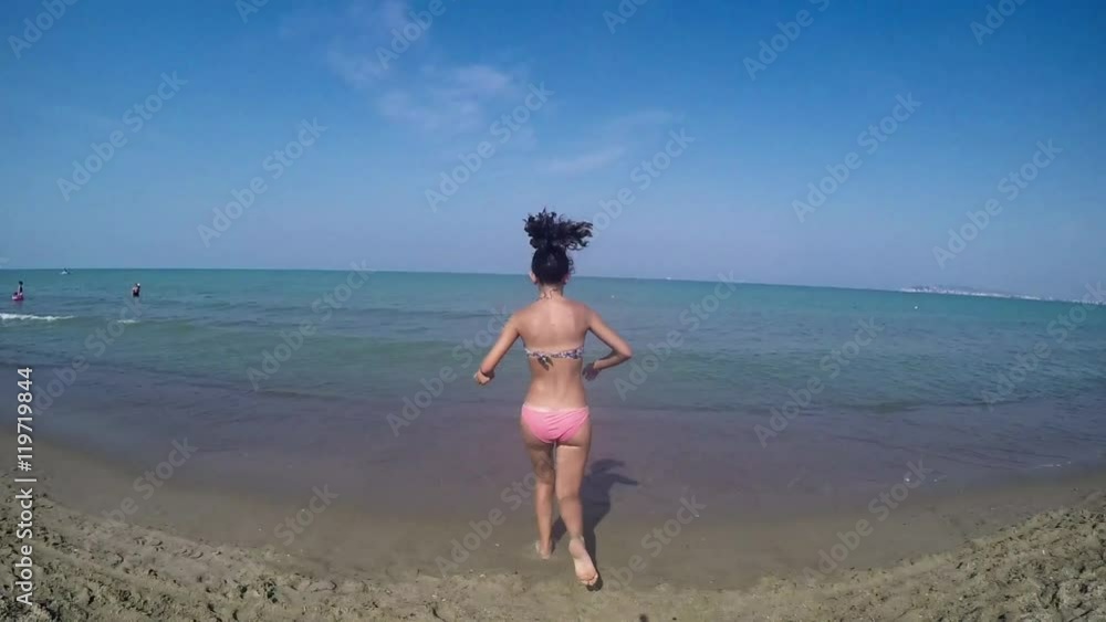 Handheld shot of Girl running into the sea Handheld shot of Girl running into the sea