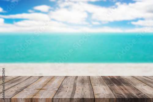 Wood table top on blurred blue sea and white sand beach backgrou