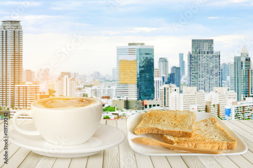 Cups of smile coffee on white wood table with cityscape of buildind as background photo